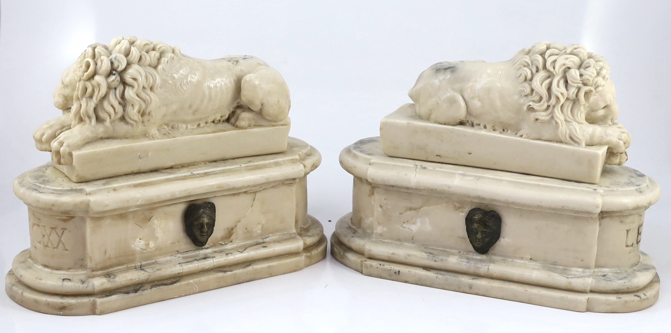 After the Antique. A pair of marble resin models of the Medici lions, each seated upon an oblong plinth, applied with bronze masks, inscribed LECXX, 41cm long, 15cm deep, 29cm high